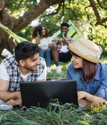 multiracial-friends-with-laptop-relaxing-at-garden-MBZCHJ5.jpg